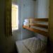 2e slaapkamer <br>2-persoonsbed met een 1-persoonsbed erboven; open kledingkast, raam met luik en verduisterend gordijn
