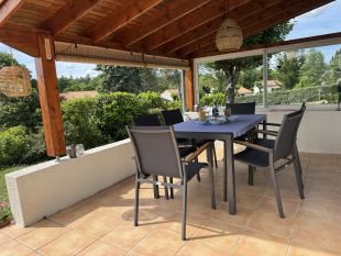 Eettafel met stoelen onder overkapping op terras
