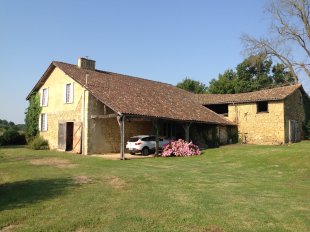 Achterzijde van de vakantiewoning <br>Ruime carport met bijkomende ingang huis.